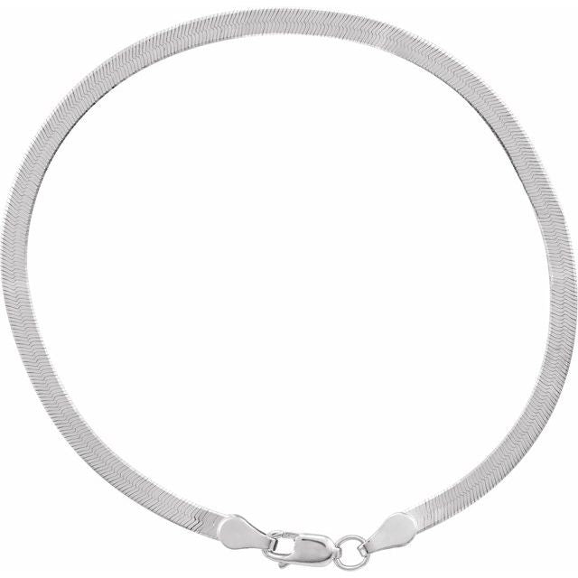 Close-up of white gold herringbone necklace texture showing interwoven gold links.