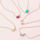 Multiple emerald-cut birthstone necklaces styled together, editorial layering shot