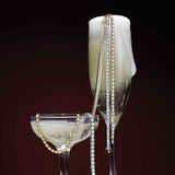 Lab-grown diamond tennis bracelet layered with other bracelets on champagne glasses